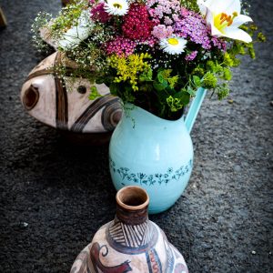 Floral arrangement in a blue vase beside handmade patterned pottery.