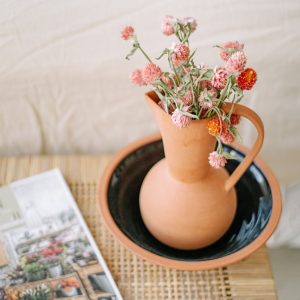 Terracotta vase with dried pink flowers in a soft still-life composition.