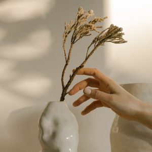 White ceramic vase holding dry branches in soft natural light.