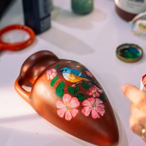 Hand-painted terracotta vase decorated with a folk-art bird and floral design.