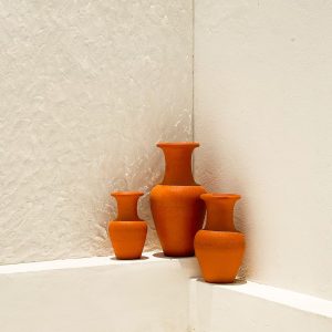 Three terracotta vases styled cleanly on a white shelf.