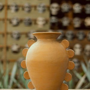 Handcrafted terracotta vase on a rustic wooden table.